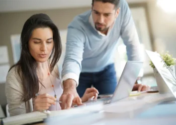 Mujer sonriente y hombre concentrado trabajando en equipo para optimizar la velocidad de carga y SEO de un sitio web peruano.