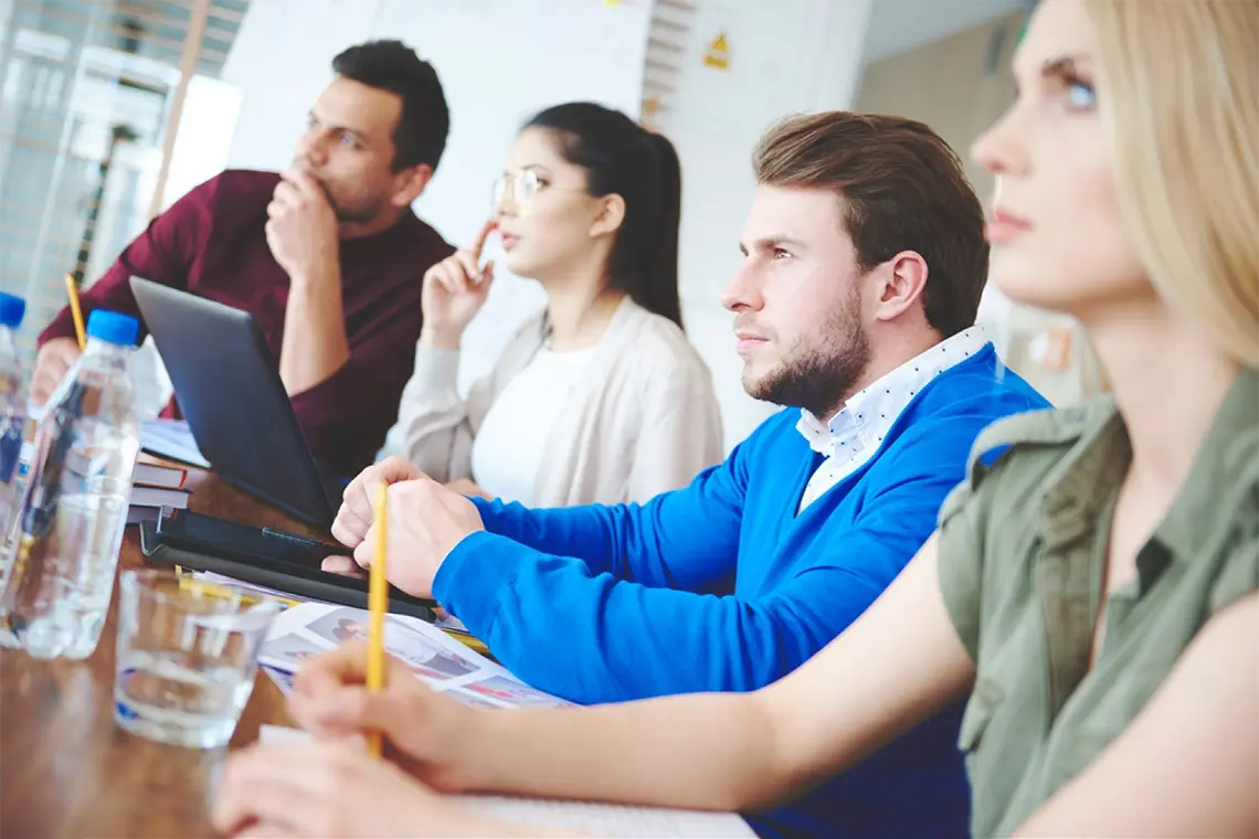 Los dos hombres del equipo prestan atención a la exposición de la mujer, tomando apuntes sobre la optimización de las metaetiquetas. [Impacto de metaetiquetas en SEO]
