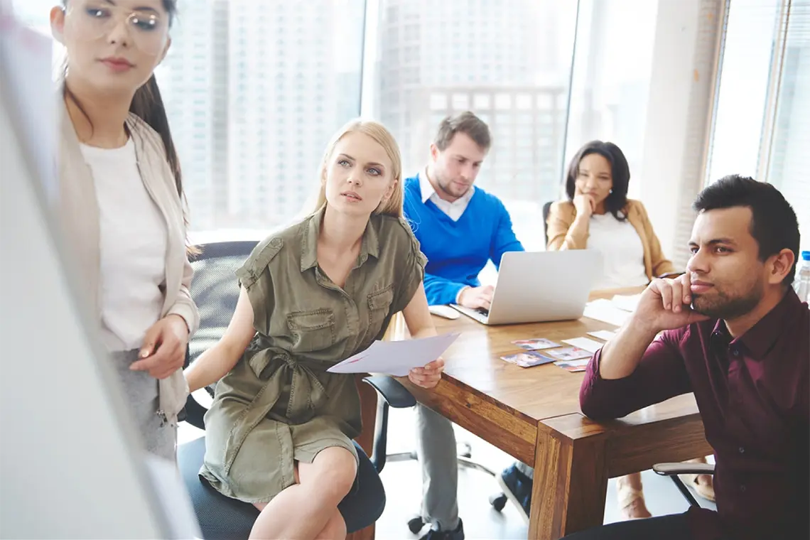 La mujer del equipo expone en una pizarra su trabajo de optimización de metaetiquetas a todo el equipo de la agencia. [Impacto de metaetiquetas en SEO]