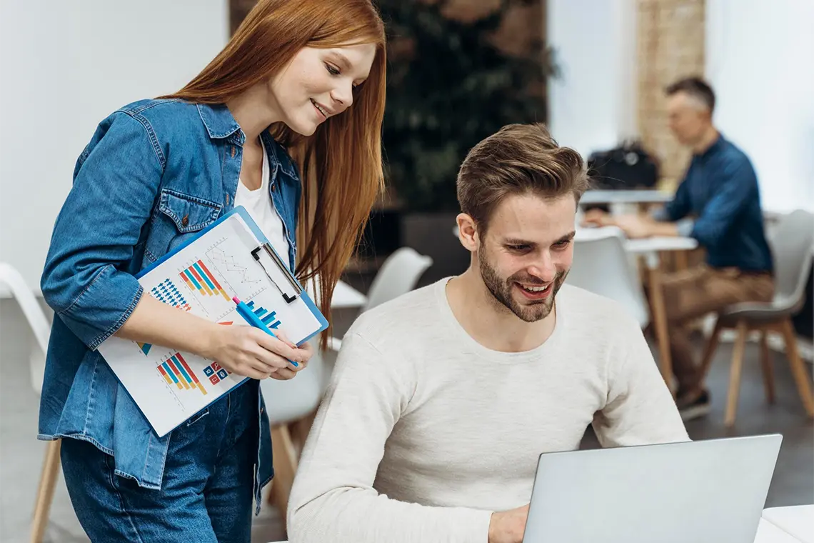 La joven, con entusiasmo, toma notas sobre las estrategias de contenido local para SEO en Arequipa que le explica el joven ya con experiencia.