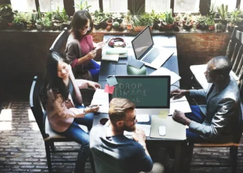 Un equipo de marketing en una oficina moderna, con un joven de barba en el centro conversando con una mujer sobre la importancia de la analítica web.