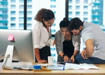 Un equipo de marketing en una oficina moderna, revisando una imagen en papel y discutiendo estrategias de optimización avanzada de imagenes.