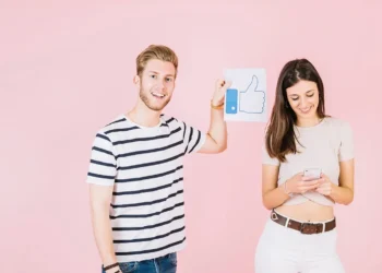 Joven sonriente mostrando un emoji de like a una chica de pelo negro en un fondo rosa, utilizando emojis para aumentar el impacto de emojis SEO en CTR local en Arequipa.