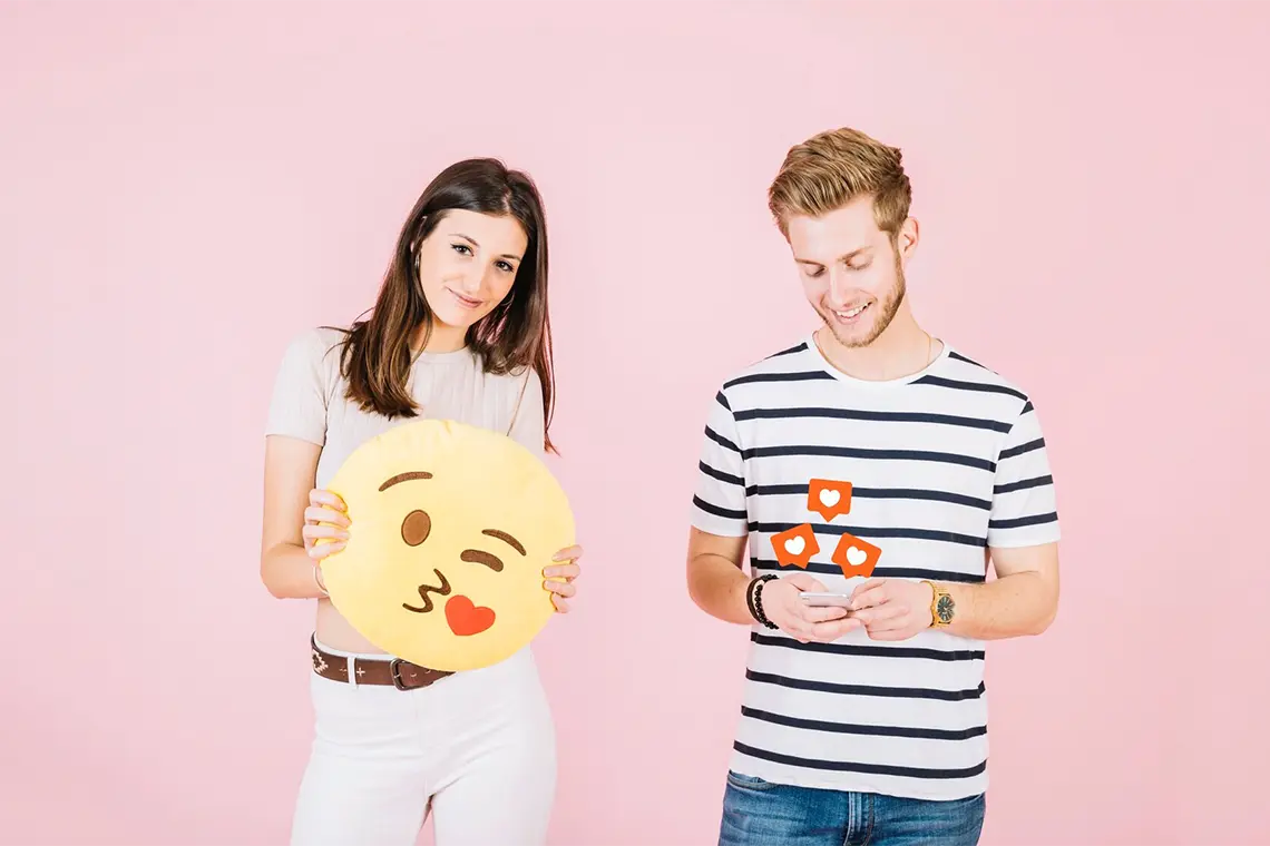 Jóvenes sonriendo y mirando a la pantalla con emojis, evidenciando el impacto positivo de los emojis SEO en el CTR local para empresas.