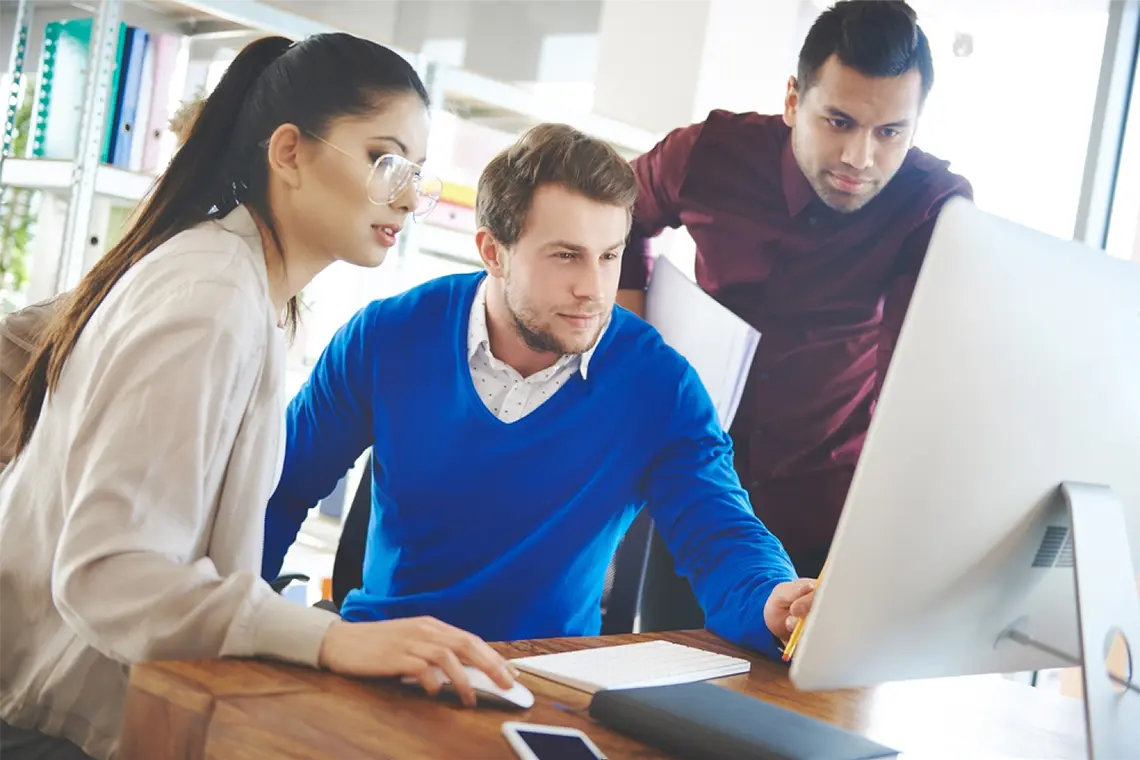 La mujer del equipo, ahora frente a la PC, muestra a sus compañeros la optimización realizada en una página web, resaltando las metaetiquetas. [Impacto de metaetiquetas en SEO]