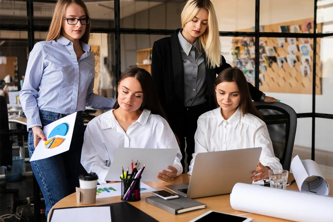 Tácticas de SEO para empresas locales Las cuatro mujeres, concentradas en su trabajo, analizan el informe en las hojas de cálculo y la laptop, implementando las tácticas SEO más eficientes para empresas locales en Arequipa.