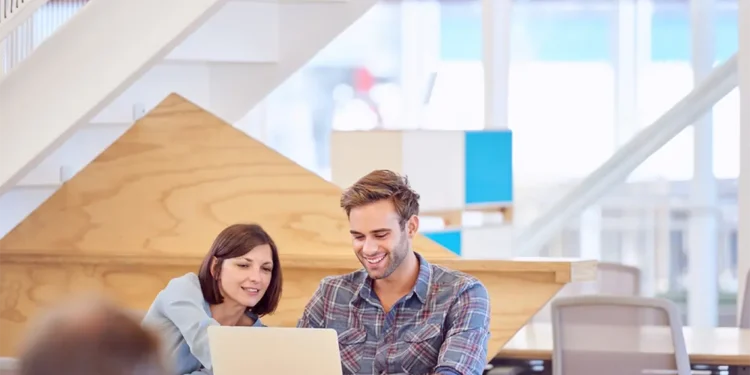 Un joven marketer, mostrando a su supervisora el trabajo realizado con la utilización efectiva de enlaces internos en su laptop.