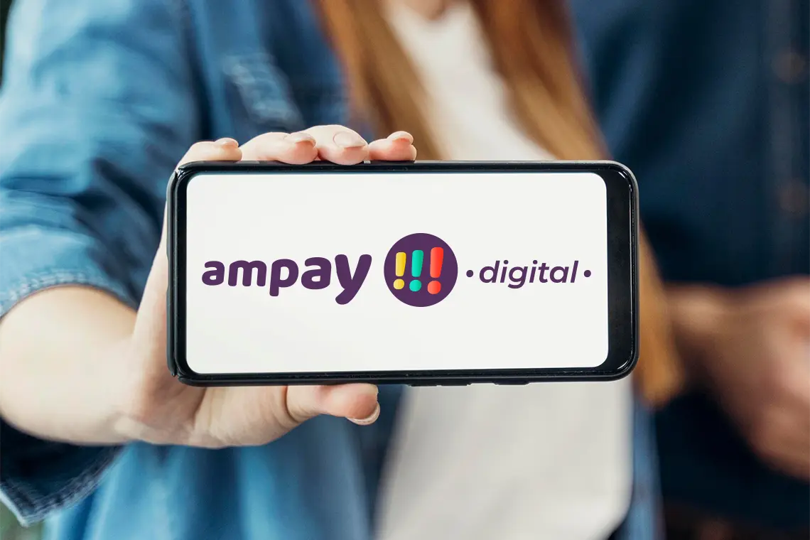La joven, con una sonrisa, sostiene un celular de forma horizontal promocionando la marca de Ampay Digital, una agencia de Marketing y SEO especializada en el mercado arequipeño.